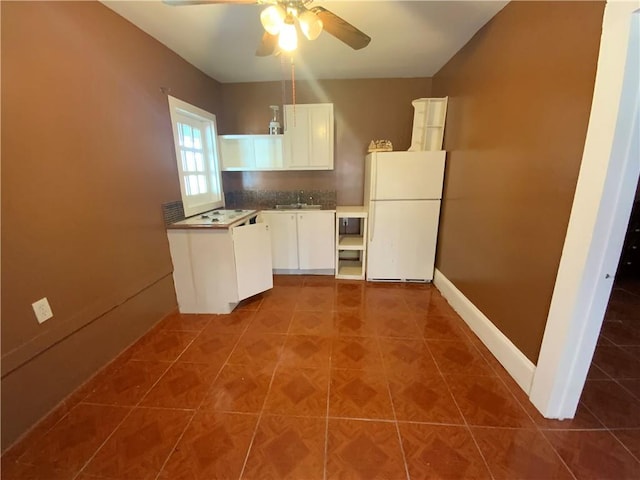 kitchen with white refrigerator, ceiling fan, white cabinets, dark tile floors, and sink