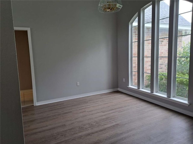 empty room featuring a notable chandelier and dark hardwood / wood-style floors