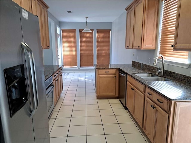 kitchen with light tile floors, kitchen peninsula, appliances with stainless steel finishes, hanging light fixtures, and sink