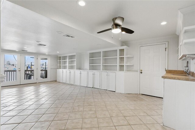 tiled spare room featuring french doors, ceiling fan, and sink