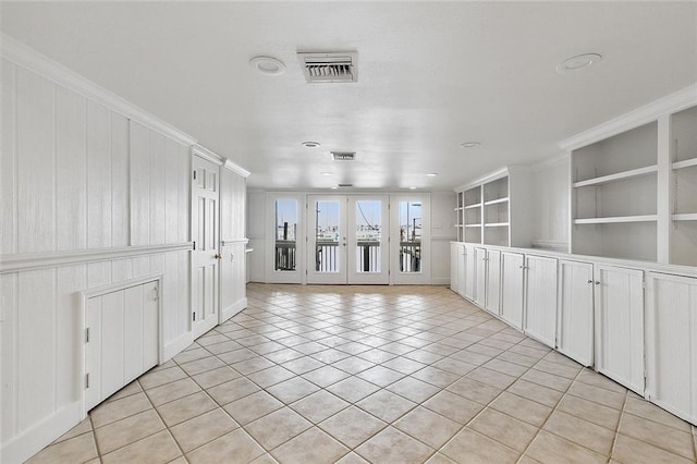 empty room with light tile flooring, ornamental molding, and french doors