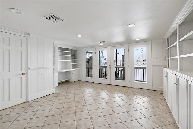 tiled spare room featuring plenty of natural light, french doors, and built in shelves