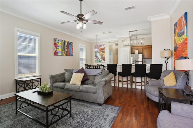 living room with crown molding, dark hardwood / wood-style flooring, and ceiling fan with notable chandelier