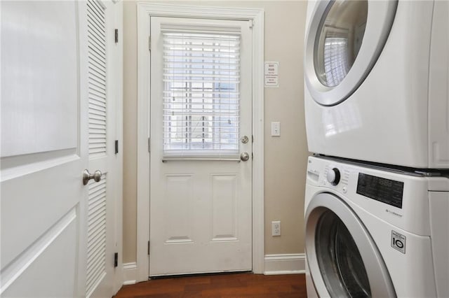 washroom featuring plenty of natural light, dark hardwood / wood-style flooring, and stacked washer and dryer