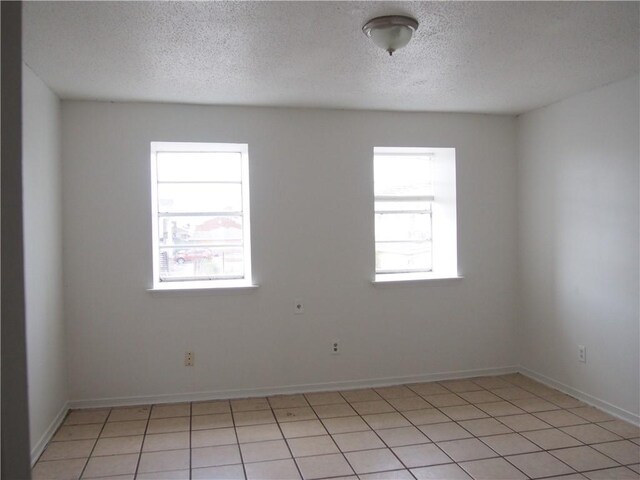 tiled spare room featuring a healthy amount of sunlight and a textured ceiling