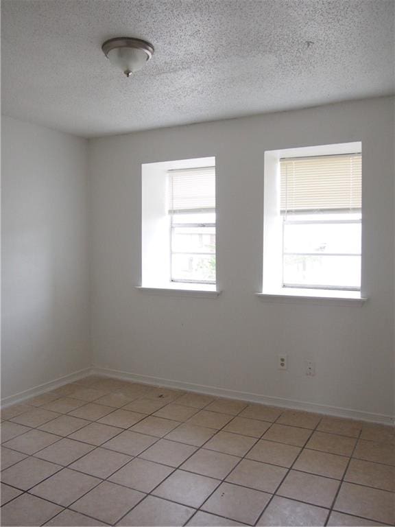 tiled empty room with a textured ceiling