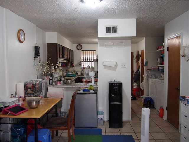 kitchen featuring a textured ceiling, light tile floors, washer and dryer, and dark brown cabinets