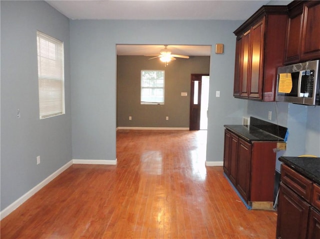 kitchen featuring dark stone countertops, ceiling fan, and light wood-type flooring