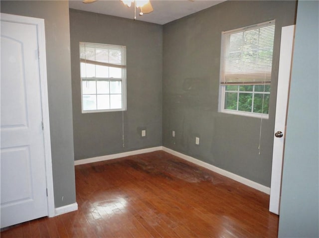 unfurnished room with dark hardwood / wood-style flooring, a healthy amount of sunlight, and ceiling fan