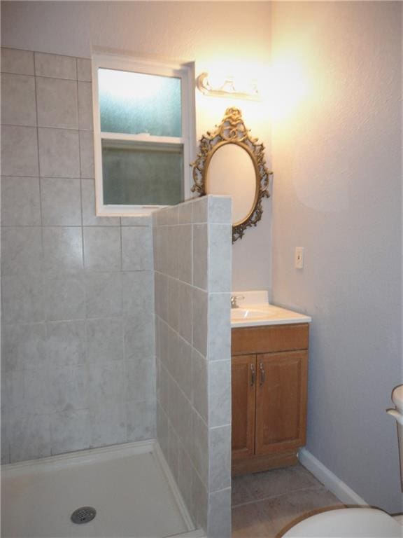 bathroom featuring toilet, tile floors, a tile shower, and vanity