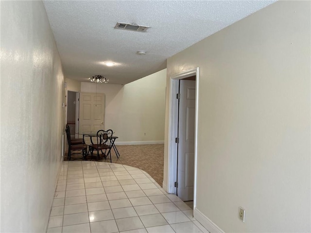 hall featuring a textured ceiling and light tile patterned floors