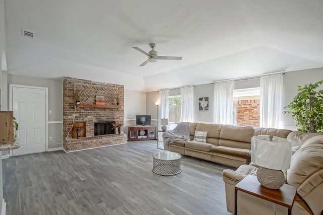 living room with brick wall, ceiling fan, wood-type flooring, and a fireplace