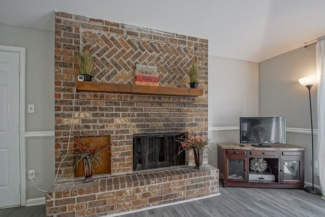 living room with a brick fireplace and dark hardwood / wood-style flooring