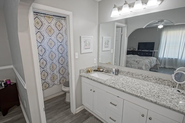 bathroom featuring oversized vanity, toilet, wood-type flooring, and ceiling fan