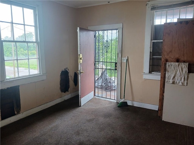 doorway with dark carpet and crown molding