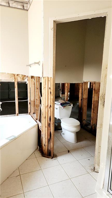 bathroom featuring a tub, toilet, and tile flooring