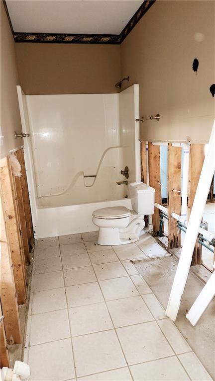 bathroom featuring tile flooring, shower / tub combination, and toilet