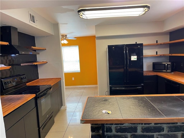 kitchen with ceiling fan, light tile floors, black appliances, and wall chimney exhaust hood