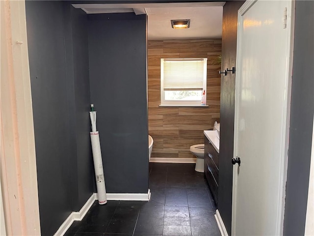 bathroom with tile flooring, toilet, wood walls, and vanity