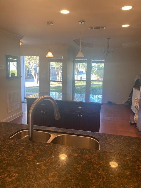 kitchen featuring dark stone countertops, decorative light fixtures, a healthy amount of sunlight, and sink