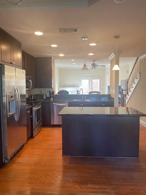 kitchen with hardwood / wood-style floors, hanging light fixtures, ceiling fan, appliances with stainless steel finishes, and dark brown cabinets