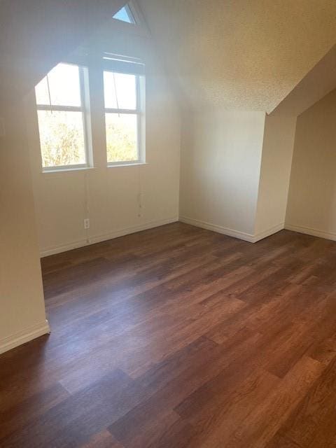 bonus room featuring a textured ceiling, dark hardwood / wood-style floors, and vaulted ceiling