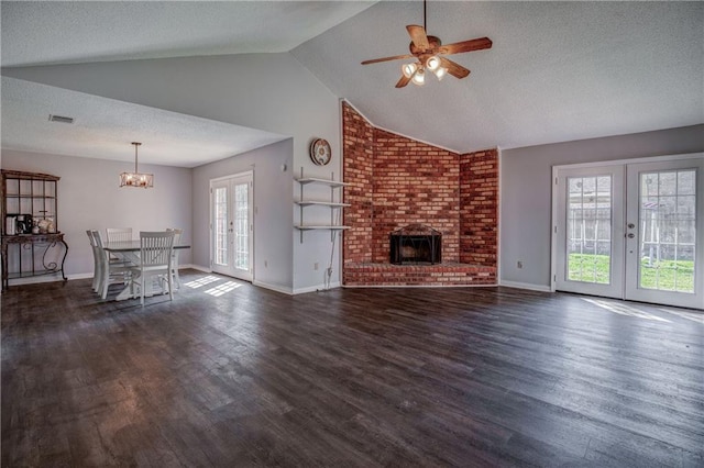 unfurnished living room featuring dark hardwood / wood-style flooring, a brick fireplace, ceiling fan with notable chandelier, and a textured ceiling