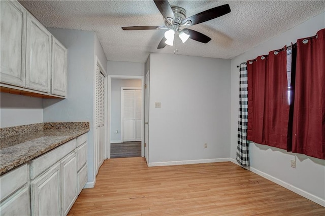 kitchen featuring white cabinetry, a textured ceiling, light hardwood / wood-style floors, and ceiling fan