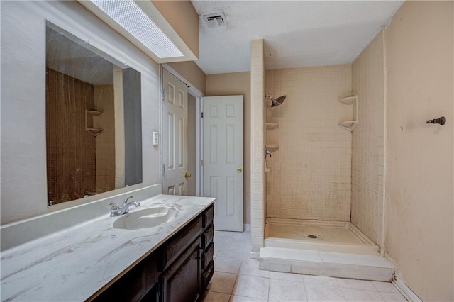 bathroom with tile floors, a tile shower, and vanity