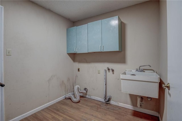 laundry room with hardwood / wood-style floors, cabinets, a textured ceiling, and sink