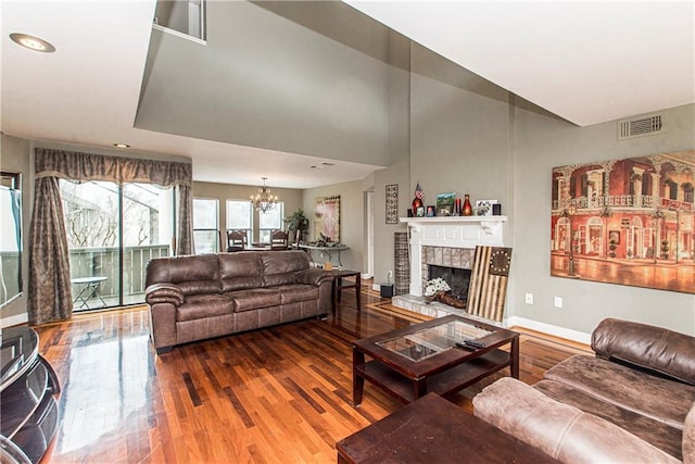 living room featuring an inviting chandelier, hardwood / wood-style flooring, and a fireplace