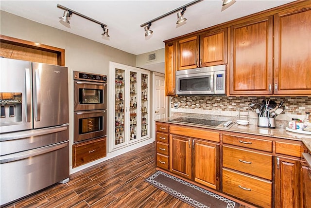 kitchen featuring track lighting, dark hardwood / wood-style floors, appliances with stainless steel finishes, and tasteful backsplash