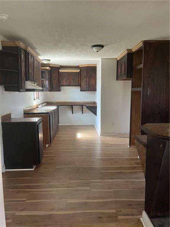 kitchen featuring sink, a textured ceiling, dark brown cabinetry, and dark hardwood / wood-style flooring