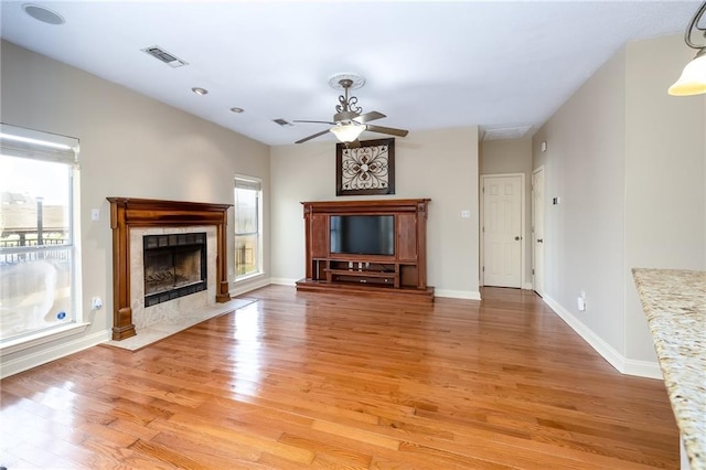 unfurnished living room featuring light hardwood / wood-style flooring, ceiling fan, and a premium fireplace