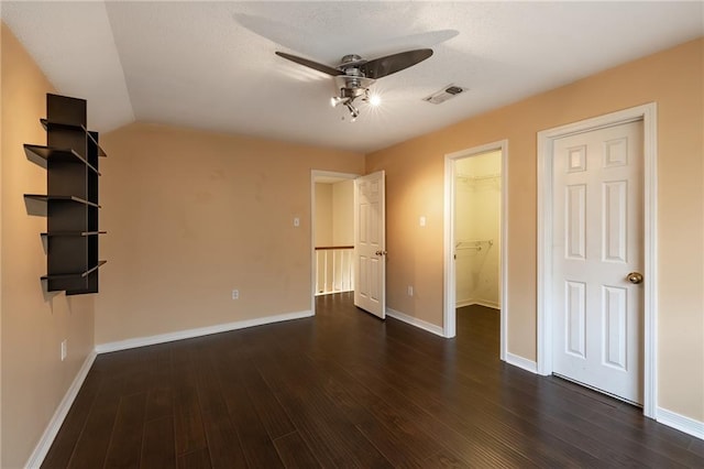 unfurnished bedroom with dark hardwood / wood-style floors, ceiling fan, a spacious closet, a closet, and lofted ceiling