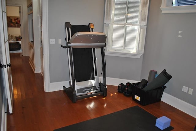 exercise room with dark hardwood / wood-style floors and a healthy amount of sunlight