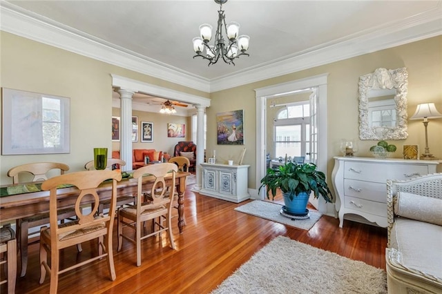 dining room featuring ceiling fan with notable chandelier, crown molding, ornate columns, and dark hardwood / wood-style flooring