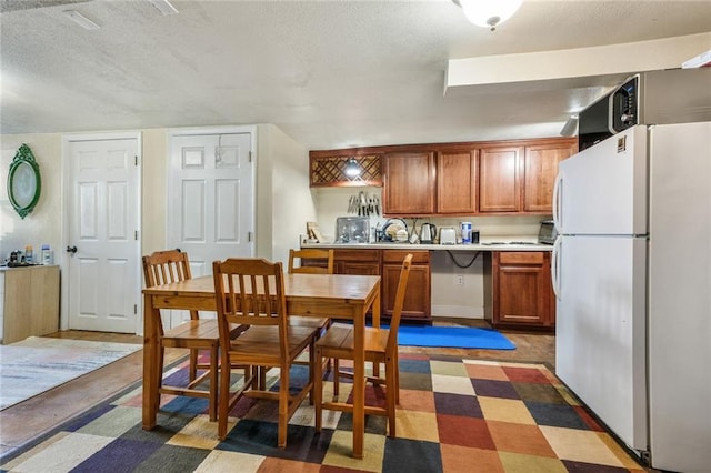 kitchen featuring white refrigerator, dark tile floors, and a textured ceiling