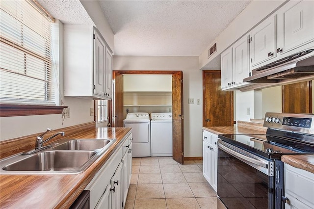 kitchen featuring sink, light tile floors, stainless steel range with electric stovetop, washing machine and clothes dryer, and white cabinetry