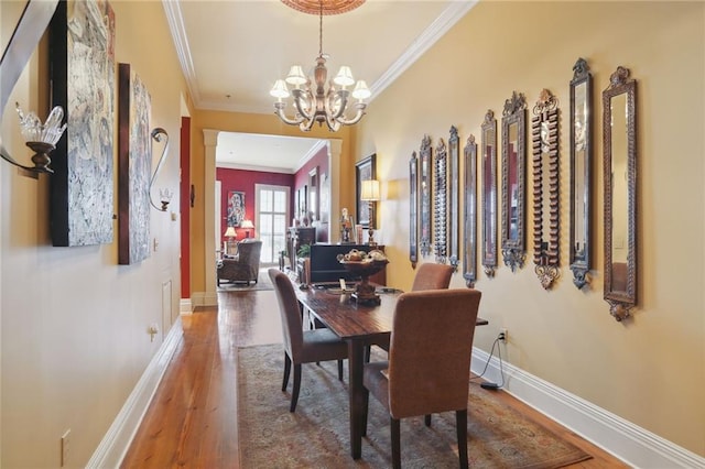 dining space featuring crown molding, a chandelier, and hardwood / wood-style flooring