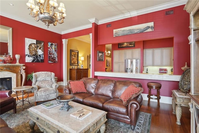 living room with an inviting chandelier, a high end fireplace, dark wood-type flooring, and ornamental molding