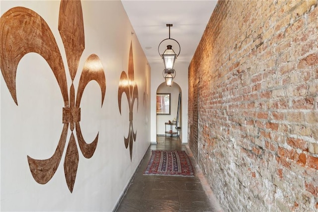 corridor with dark tile flooring and brick wall