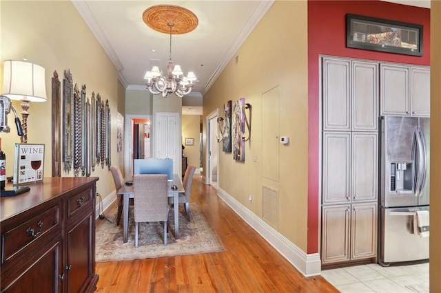 dining room with an inviting chandelier, crown molding, and light tile floors