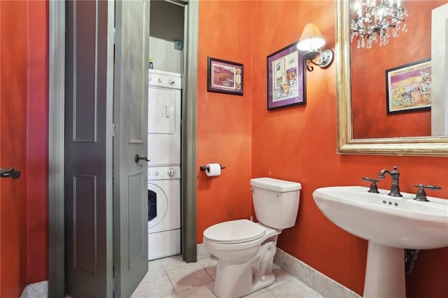 bathroom with stacked washer and dryer, toilet, and tile floors