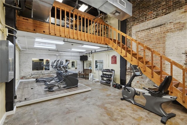 interior space with concrete flooring, brick wall, and a towering ceiling