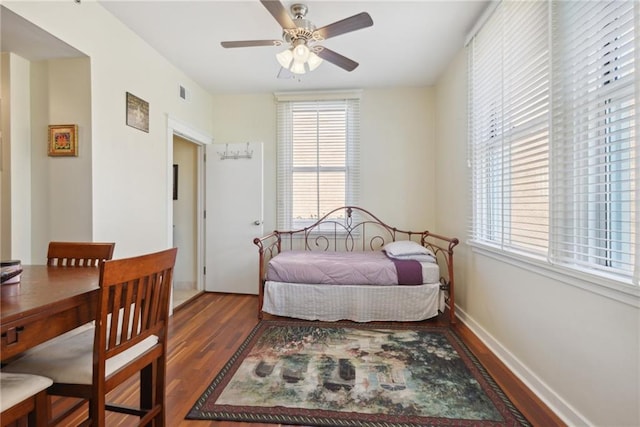 bedroom featuring dark hardwood / wood-style flooring, ceiling fan, and multiple windows