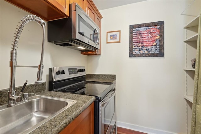 kitchen with dark stone counters, wood-type flooring, and appliances with stainless steel finishes