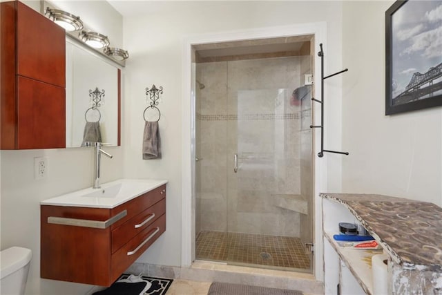 bathroom with toilet, vanity, and a shower with door