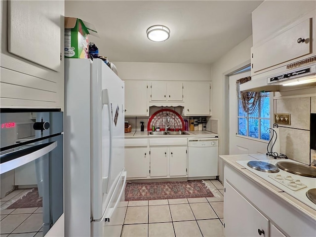 kitchen featuring white appliances, sink, light tile floors, white cabinets, and tasteful backsplash