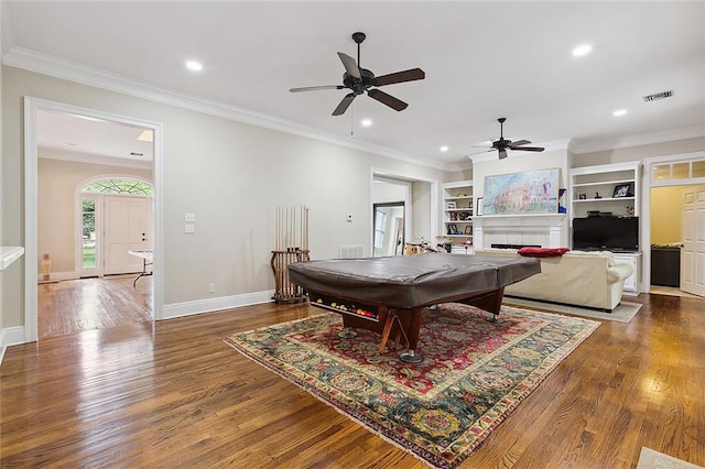 recreation room with crown molding, ceiling fan, dark hardwood / wood-style flooring, and built in shelves